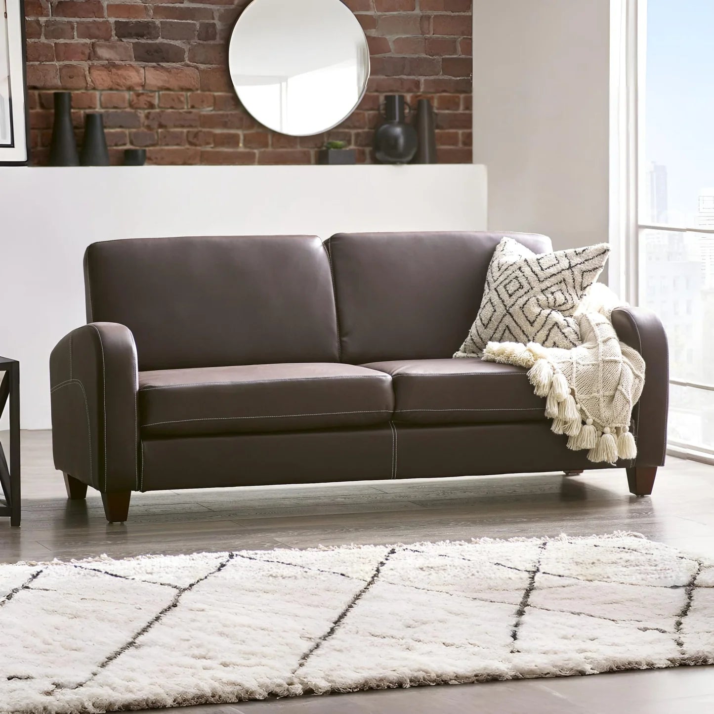 Brown leather sofa with a patterned throw blanket in a living room setting Iconic abode.